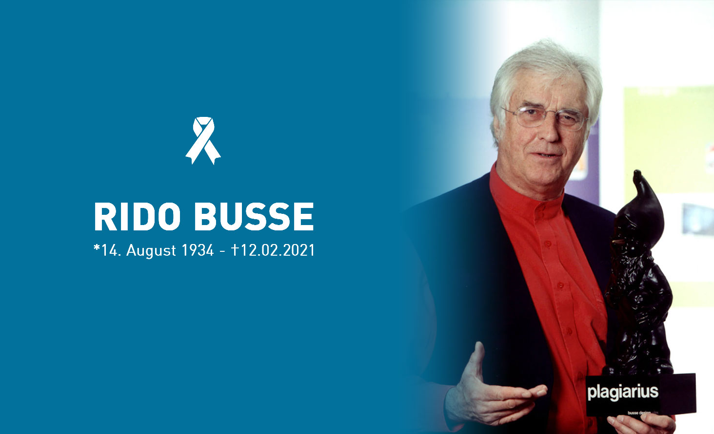 Gedenktribut an Rido Busse mit seinem Porträt und einem weißen Bandsymbol, das seine Lebensdaten vom 14. August 1934 bis zum 12. Februar 2021 zeigt. Rido Busse hält den Plagiarius-Preis.